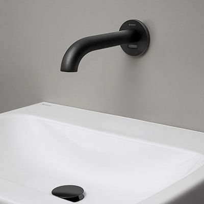 Ein schwarzer Wasserhahn, der aus der Wand kommt und einen Bewegungssensor hat.