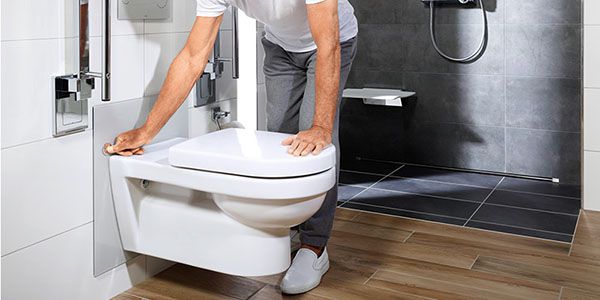 Ein Mann stellt seine Toilette per Knopfdruck an der Wand nach oben.